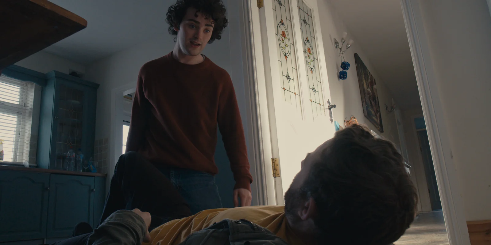 A young man stands beside a seated man in a scene from For Séamus.